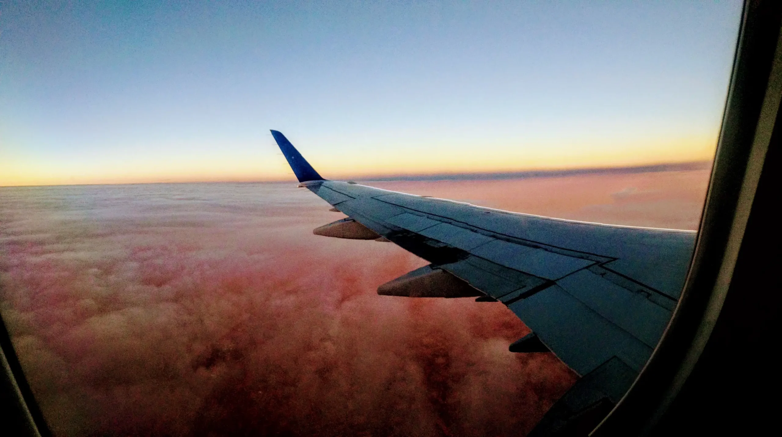 View of an airplane wing at sunset from a window seat, a flight booked on the cheapest day to fly
