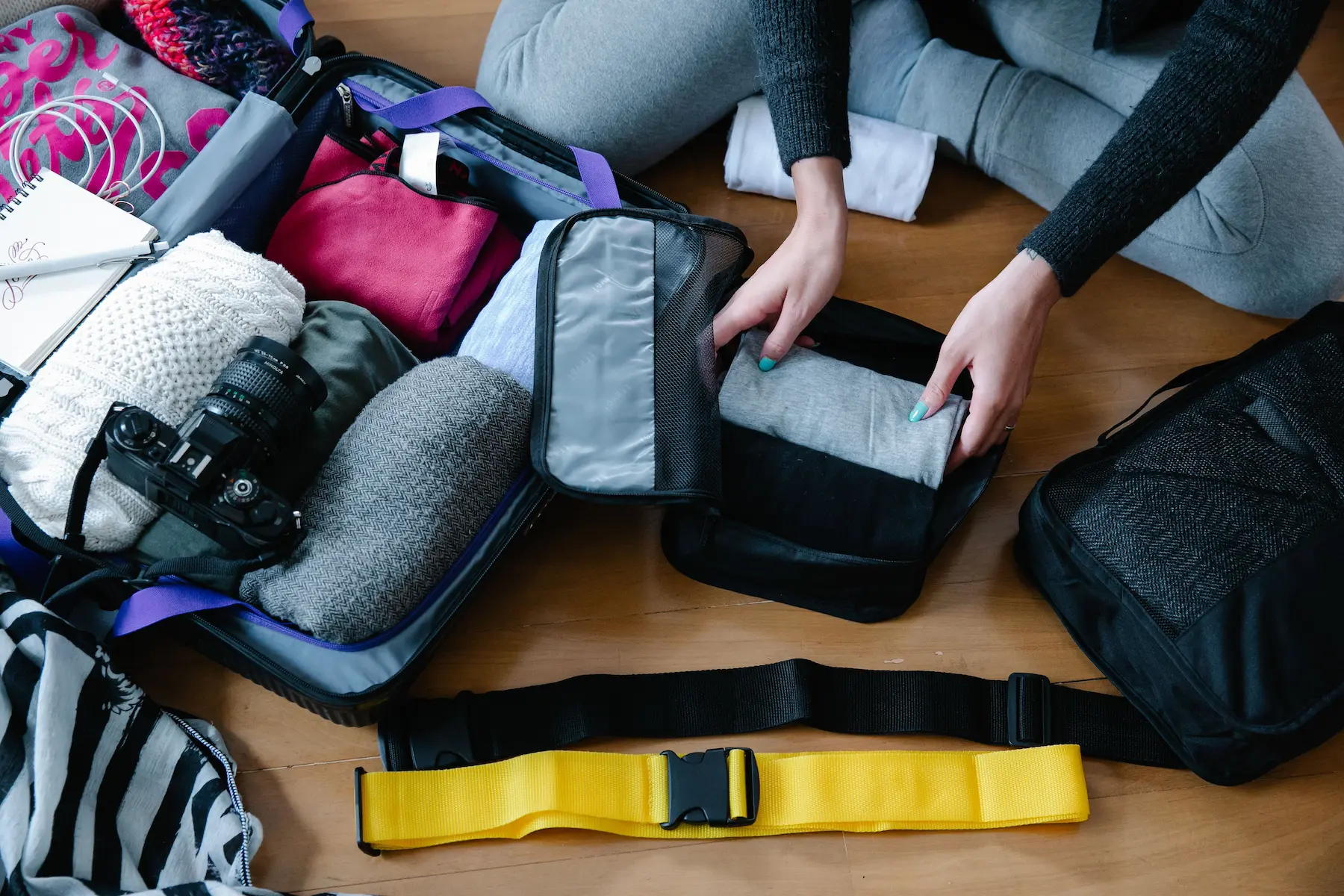 Carry on packing list: rolled clothes in packing cubes on a table