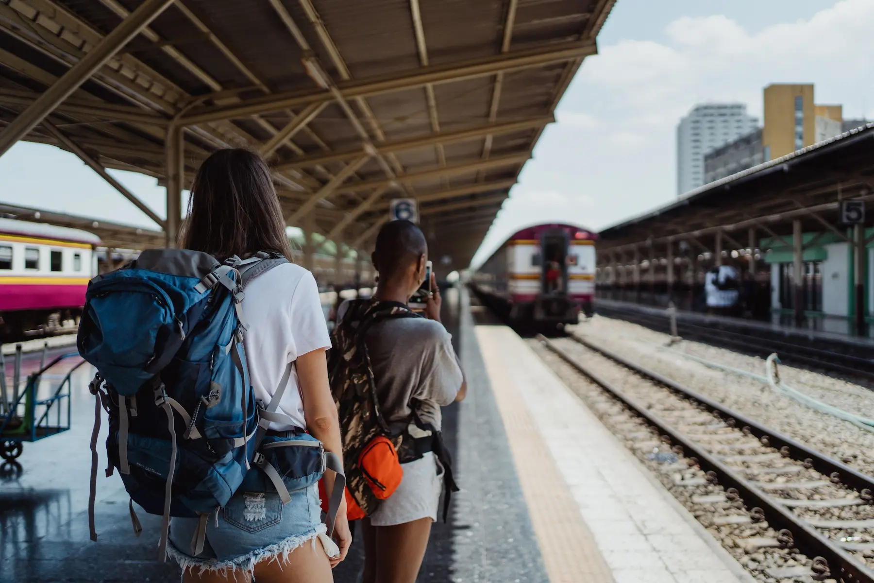 Carry on packing list: backpacker with a small backpack walking along a train platform