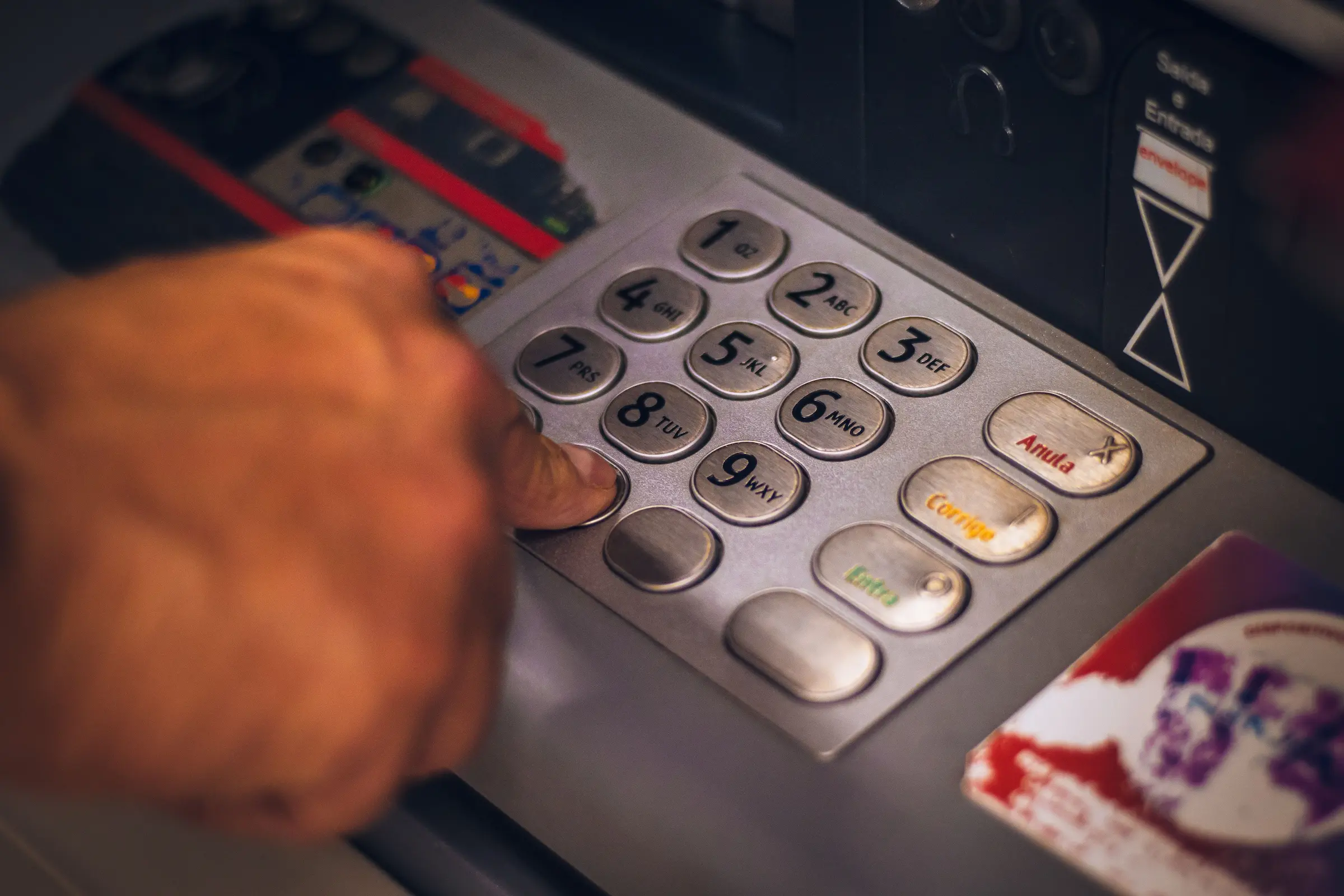 Backpacker at a city ATM working out how to avoid ATM fees abroad before withdrawing cash