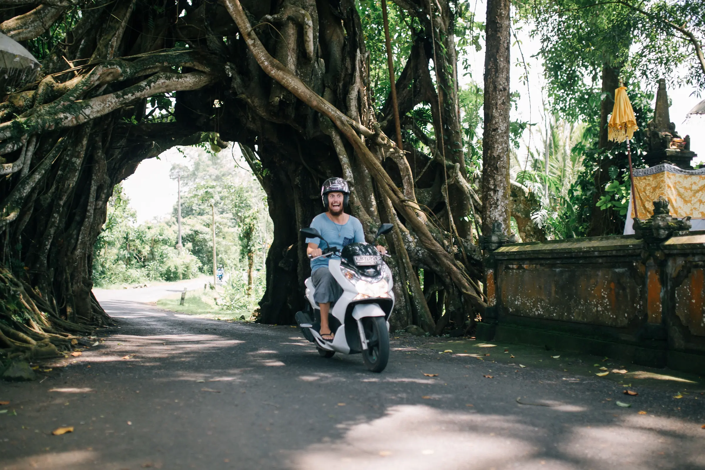 Scooter riding along a rural road, the cheapest way of getting around Bali