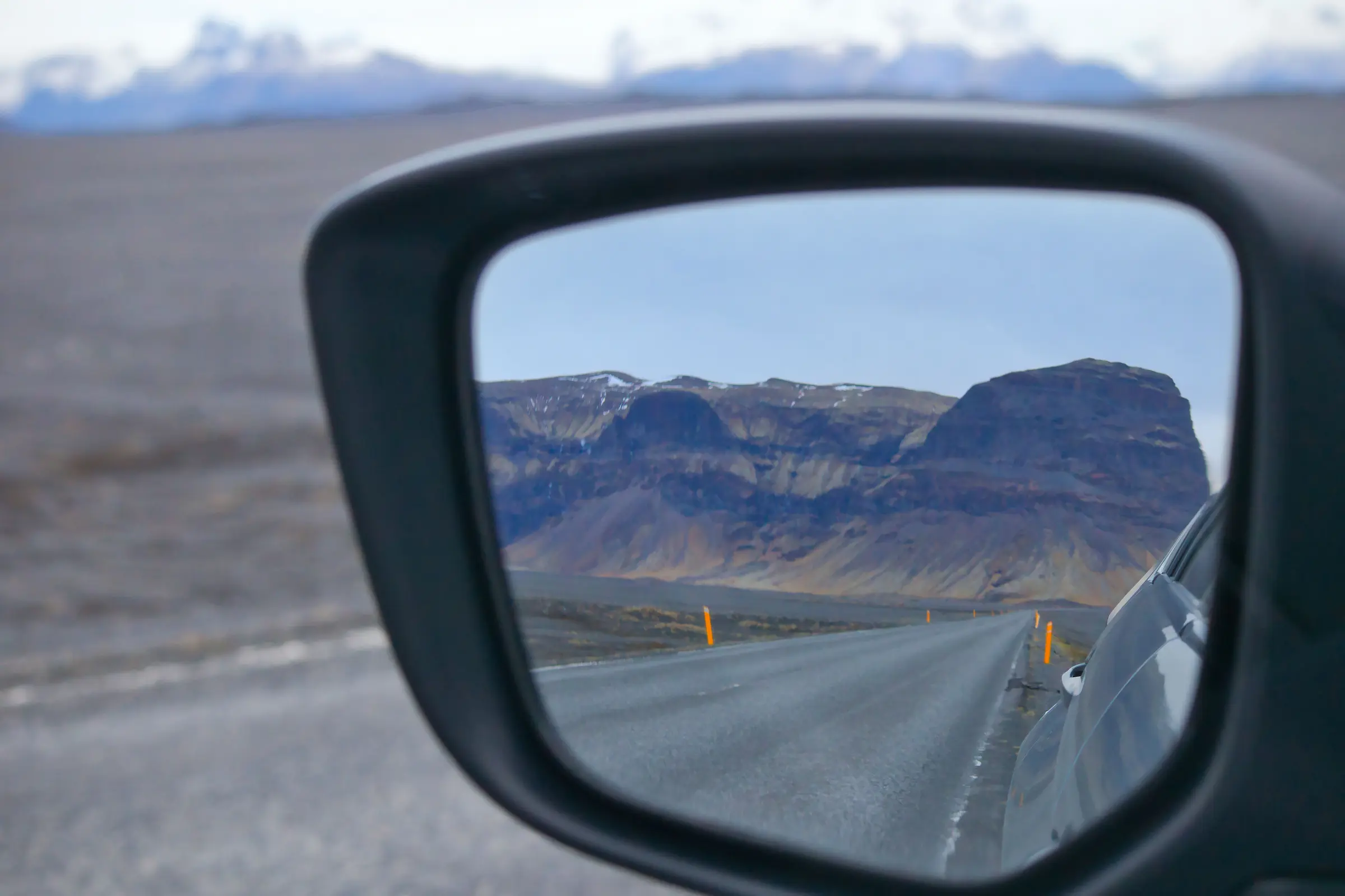 Driving the Ring Road in Iceland past a waterfall on a bright summer evening