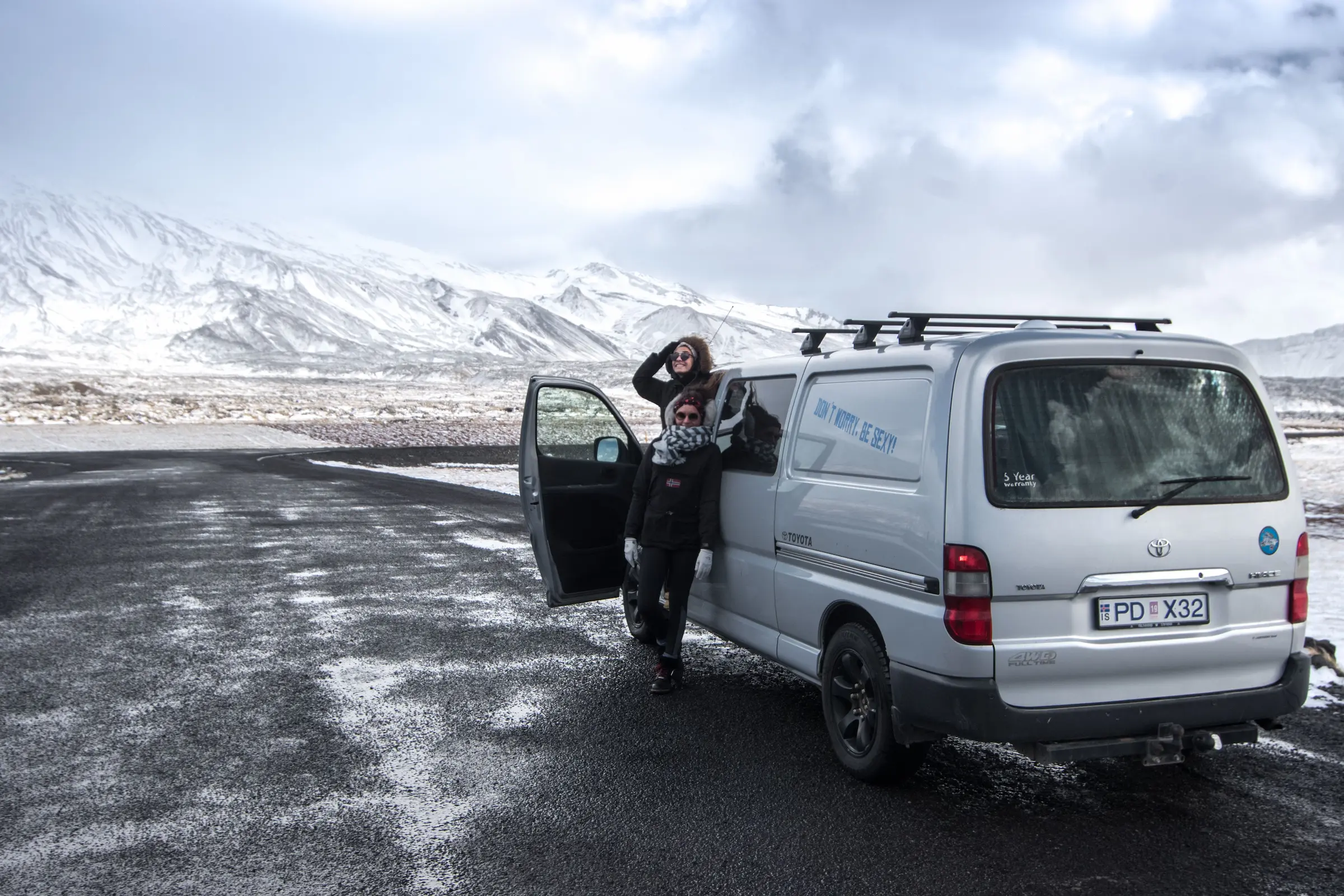 Iceland campervan road trip: small camper parked at a campsite with mountains behind